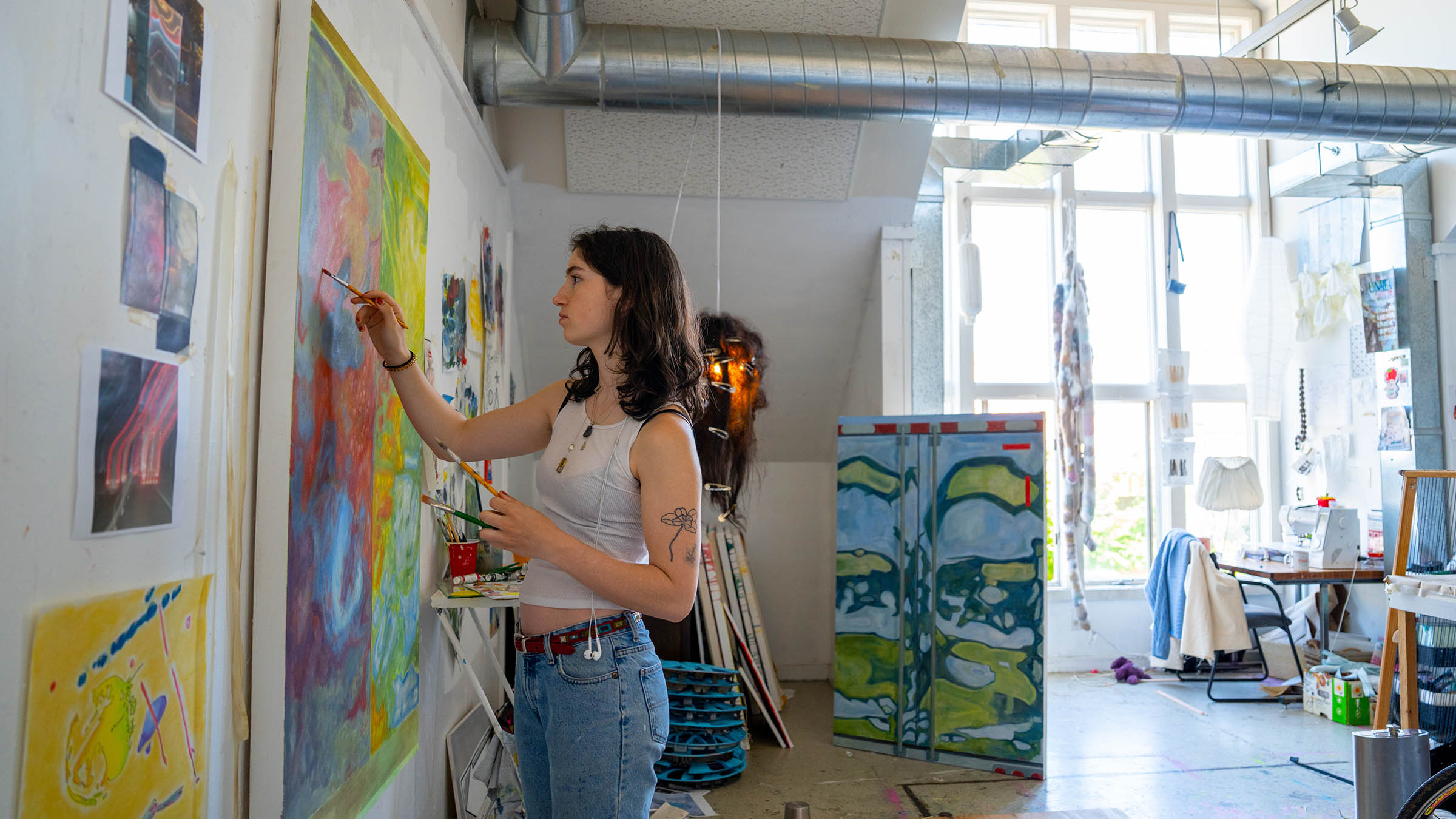 Student working on a large-scale painting in a light-filled art studio
