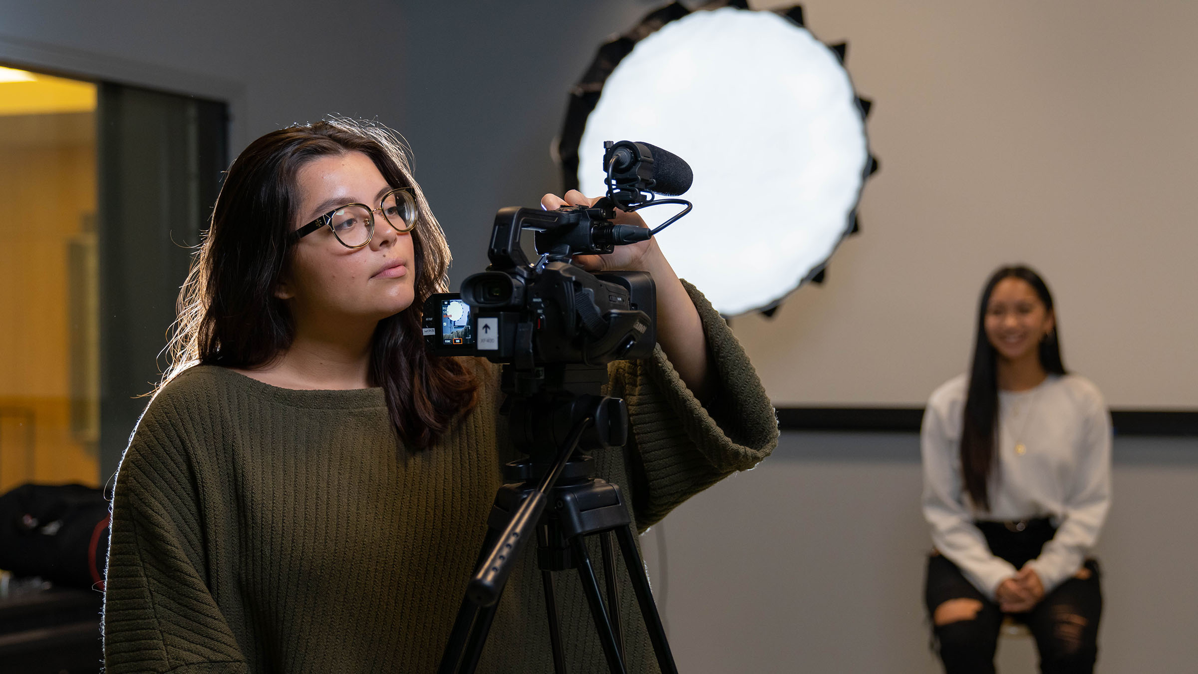 Student adjusts camera during a studio recording session