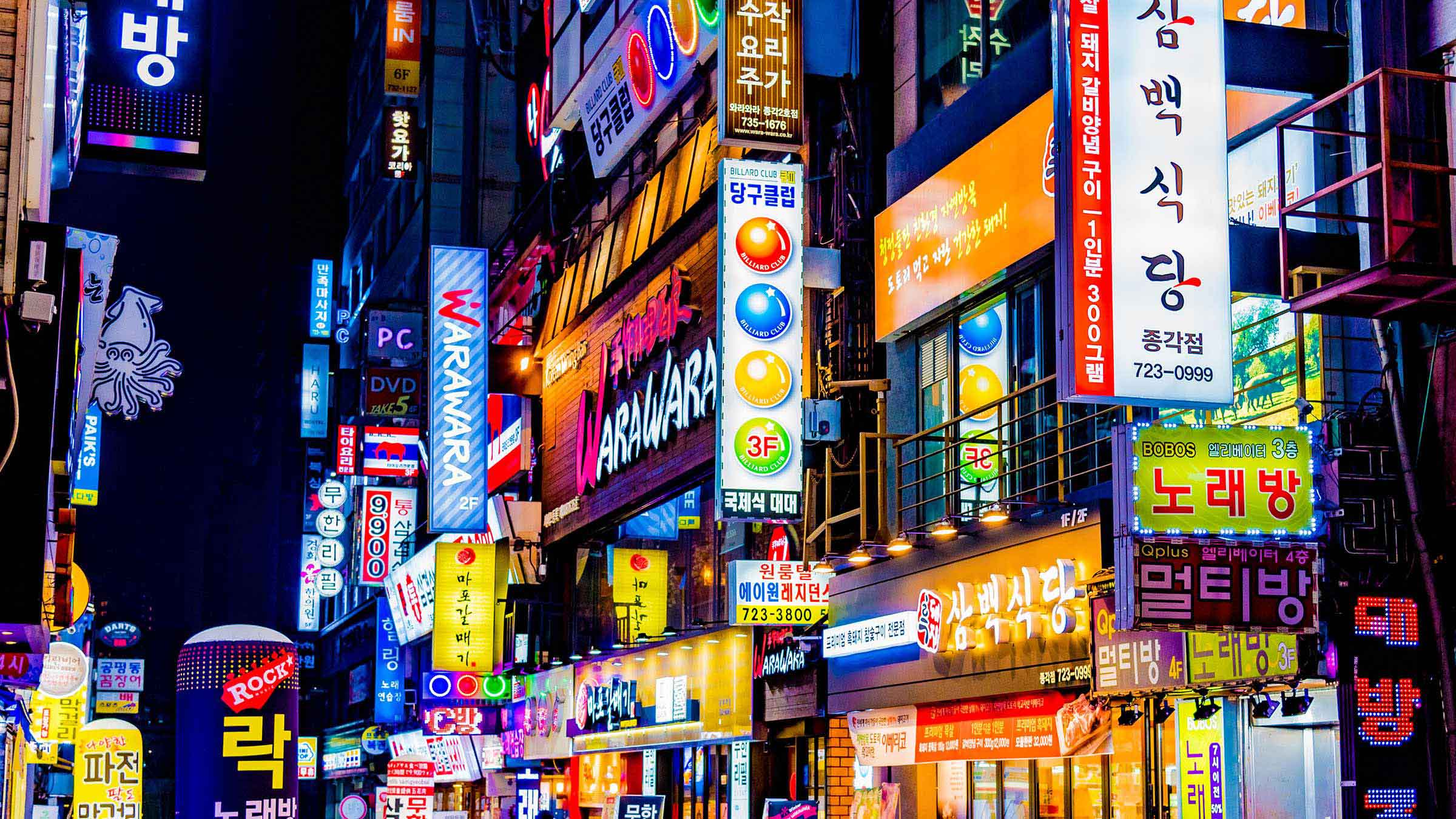 Busy urban district in South Korea featuring storefronts and illuminated signs