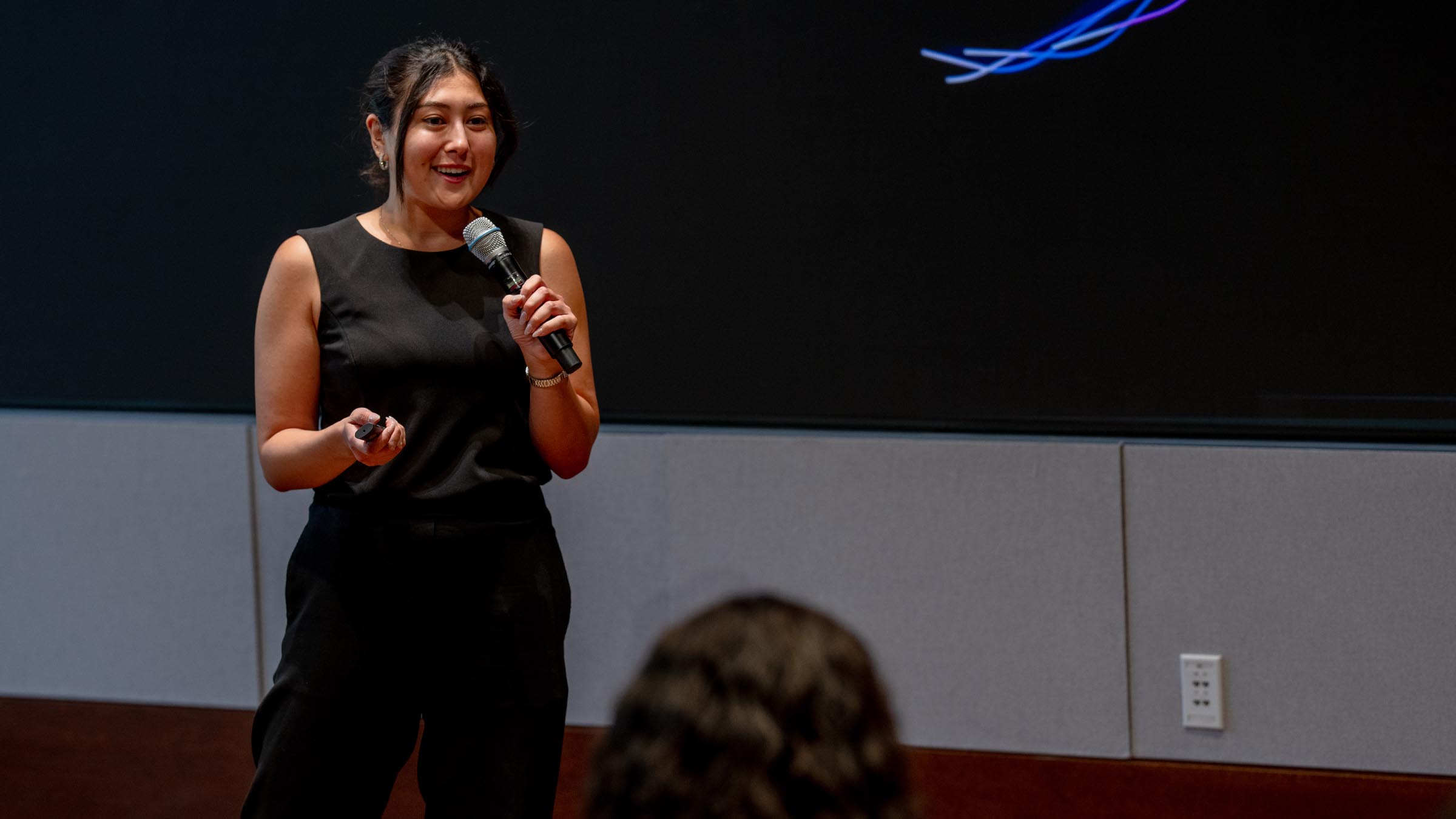 Smiling student presenting in front of a large screen