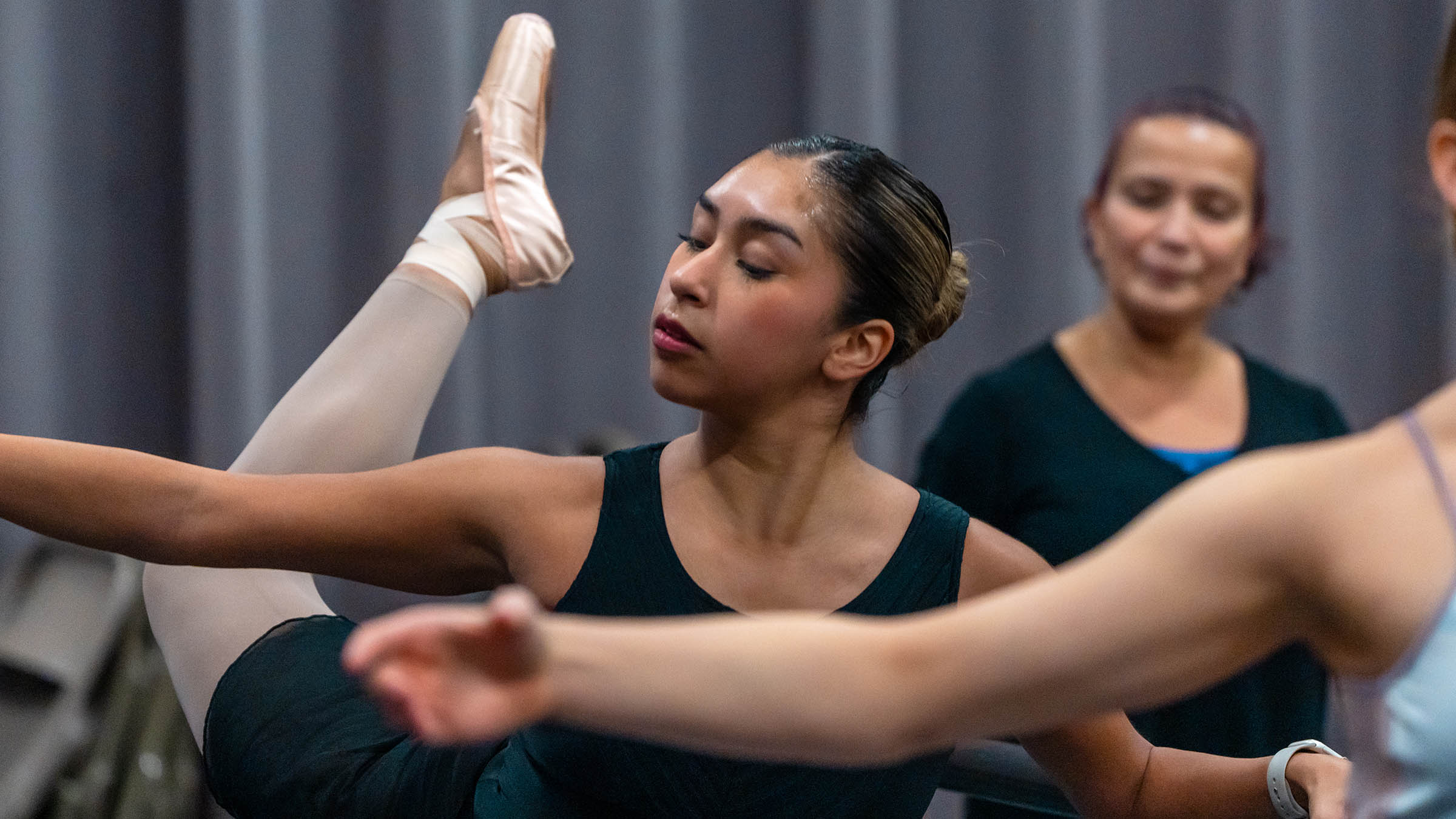 Students practicing ballet movements at the barre in a dance studio