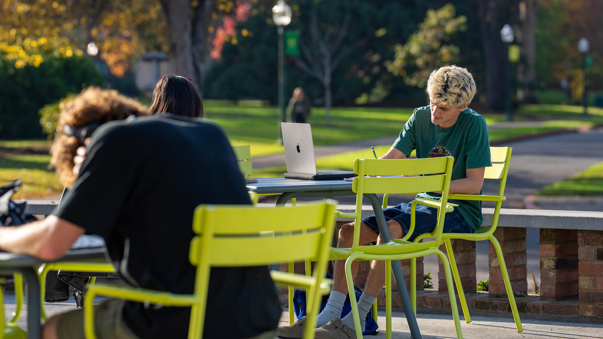 Student writing on the patio of the Erb Memorial Union on a sunny afternoon