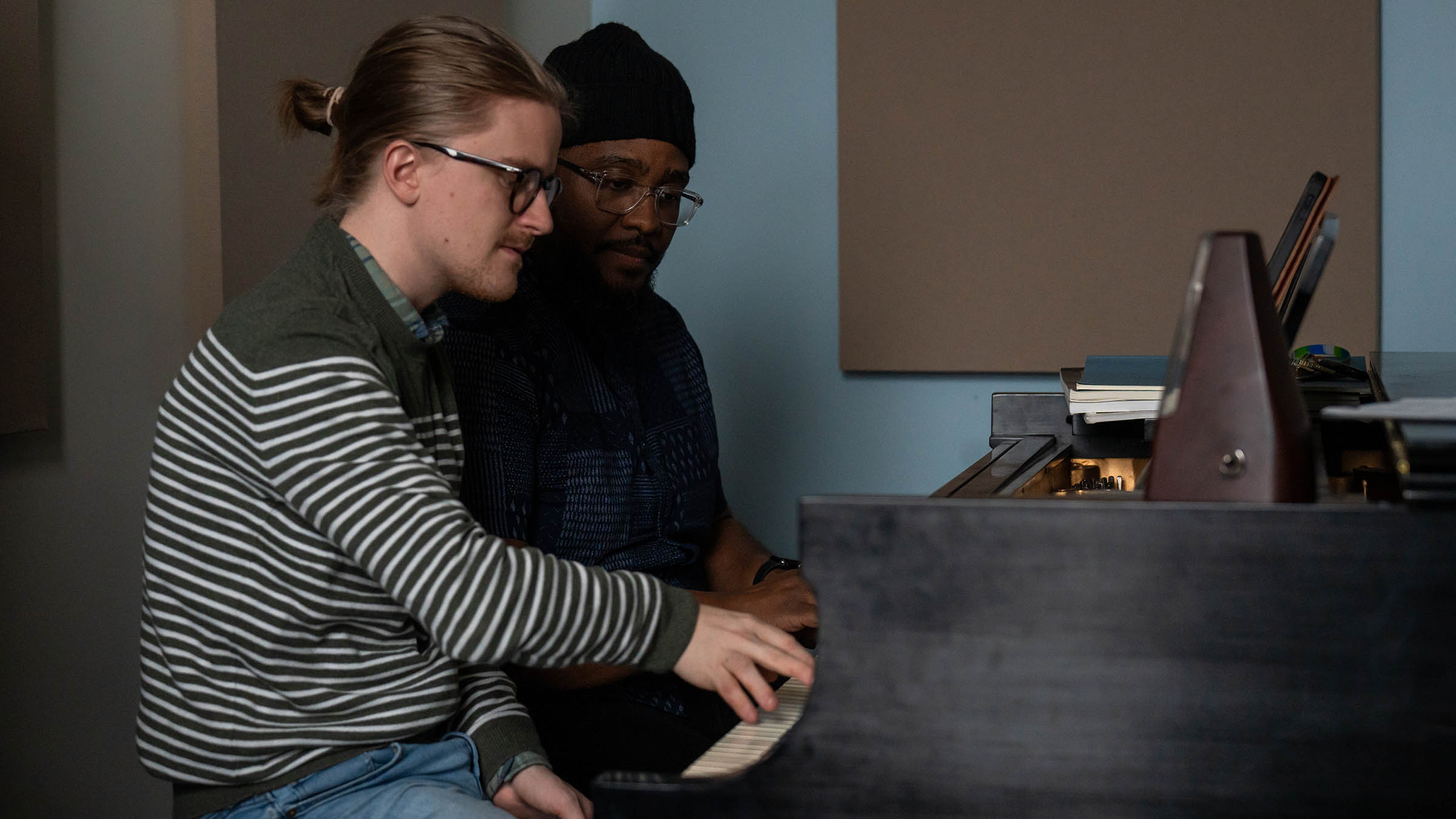 Jazz studies faculty and student at a piano in a practice room