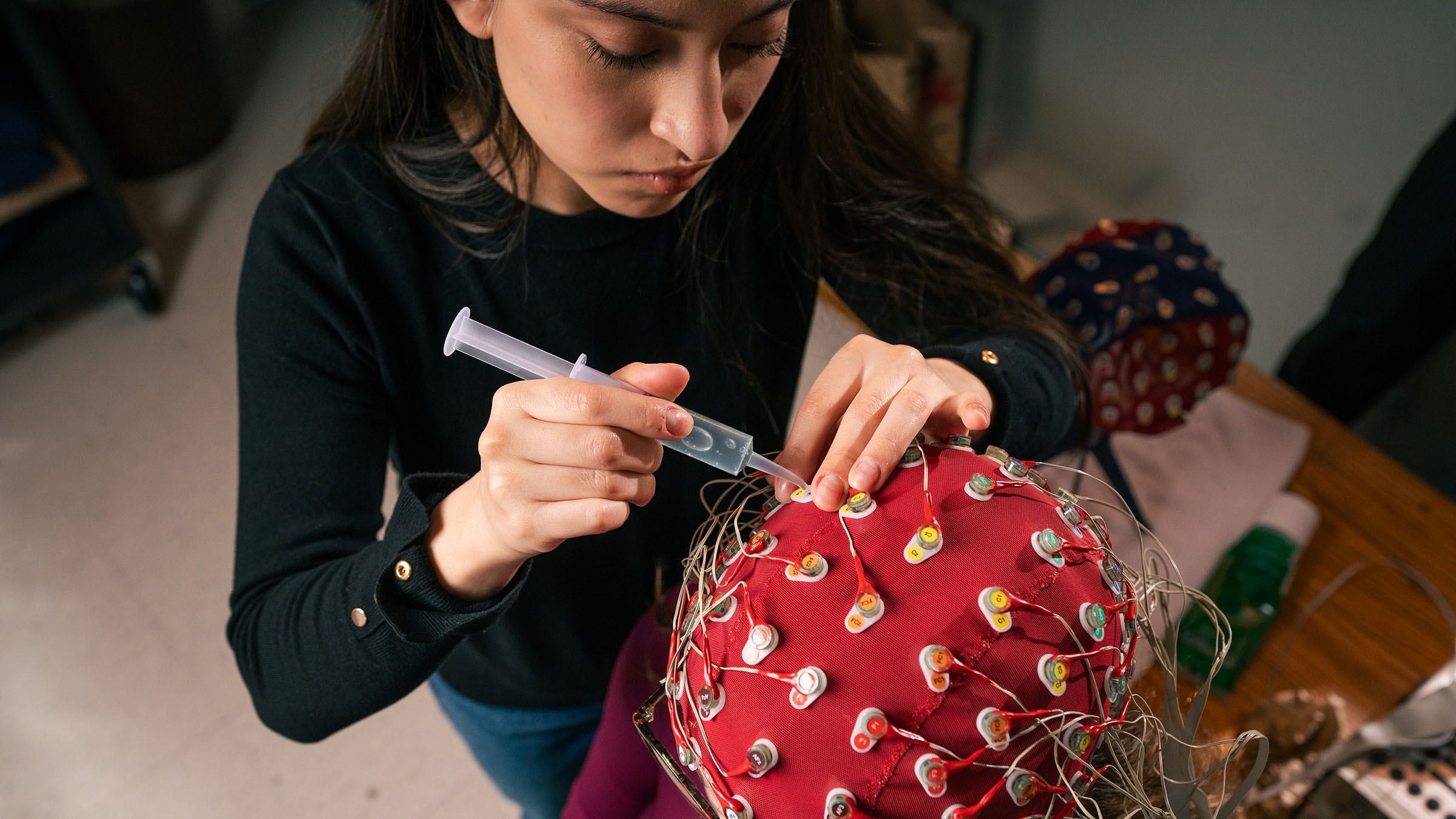 Student adjusting up an electrode cap and sensor equipment for a cognitive science experiment