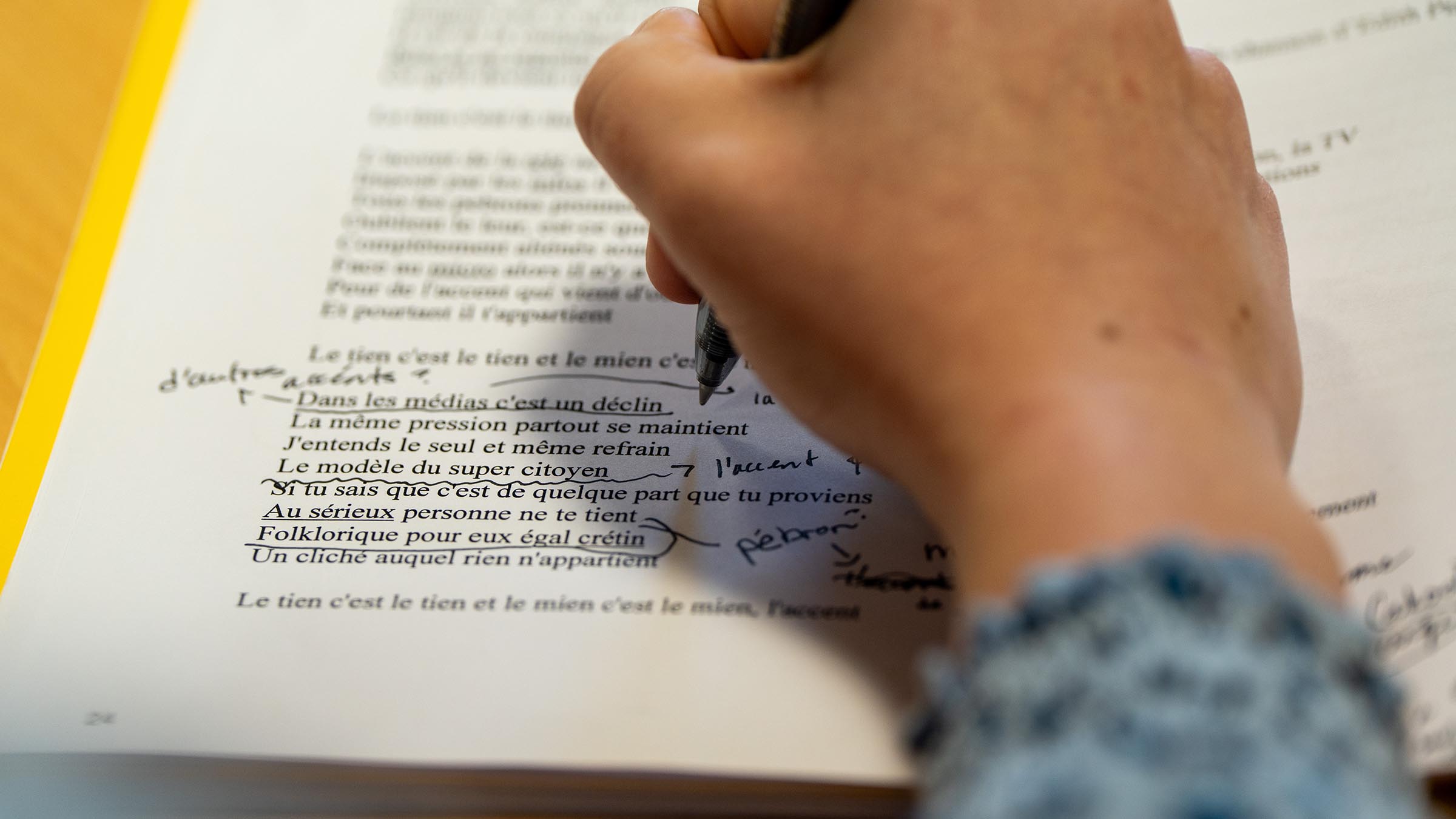 Close-up of a student annotating a French text with handwritten notes