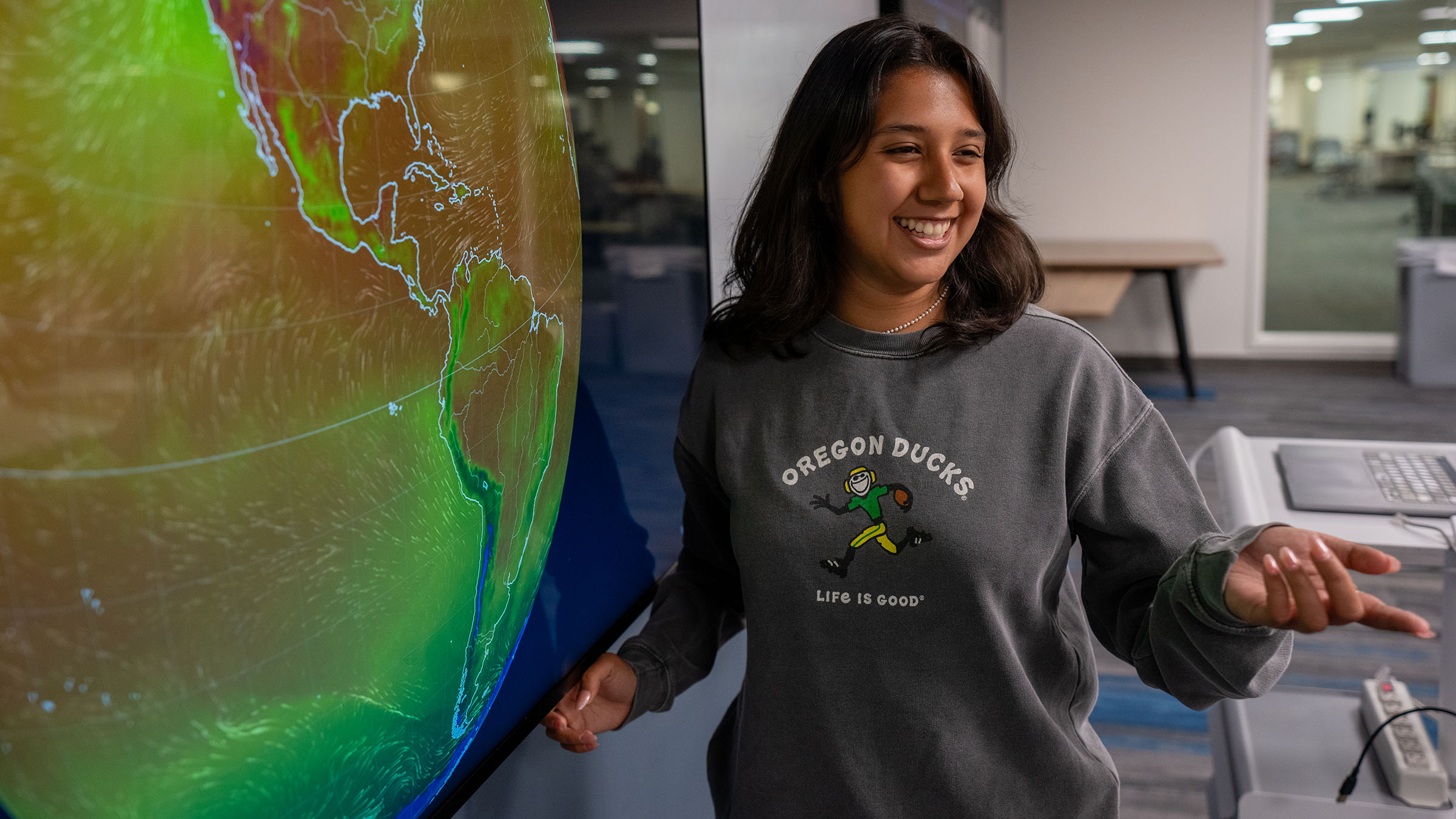 Student presenting climate and environmental data using an interactive digital globe display