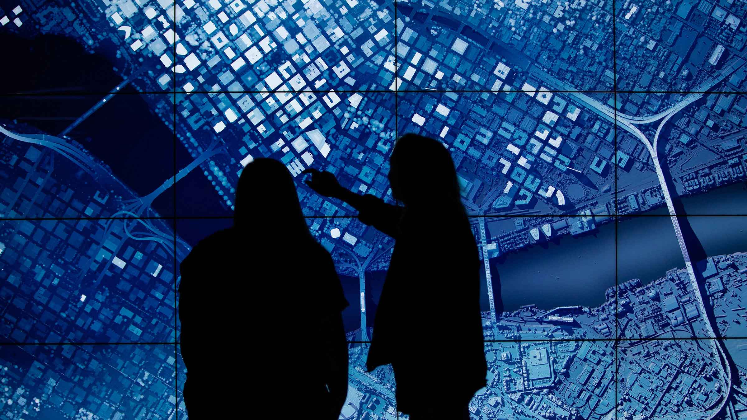 Two students examine a satellite image of a city in the Visualization Lab, using digital mapping and spatial analysis tools