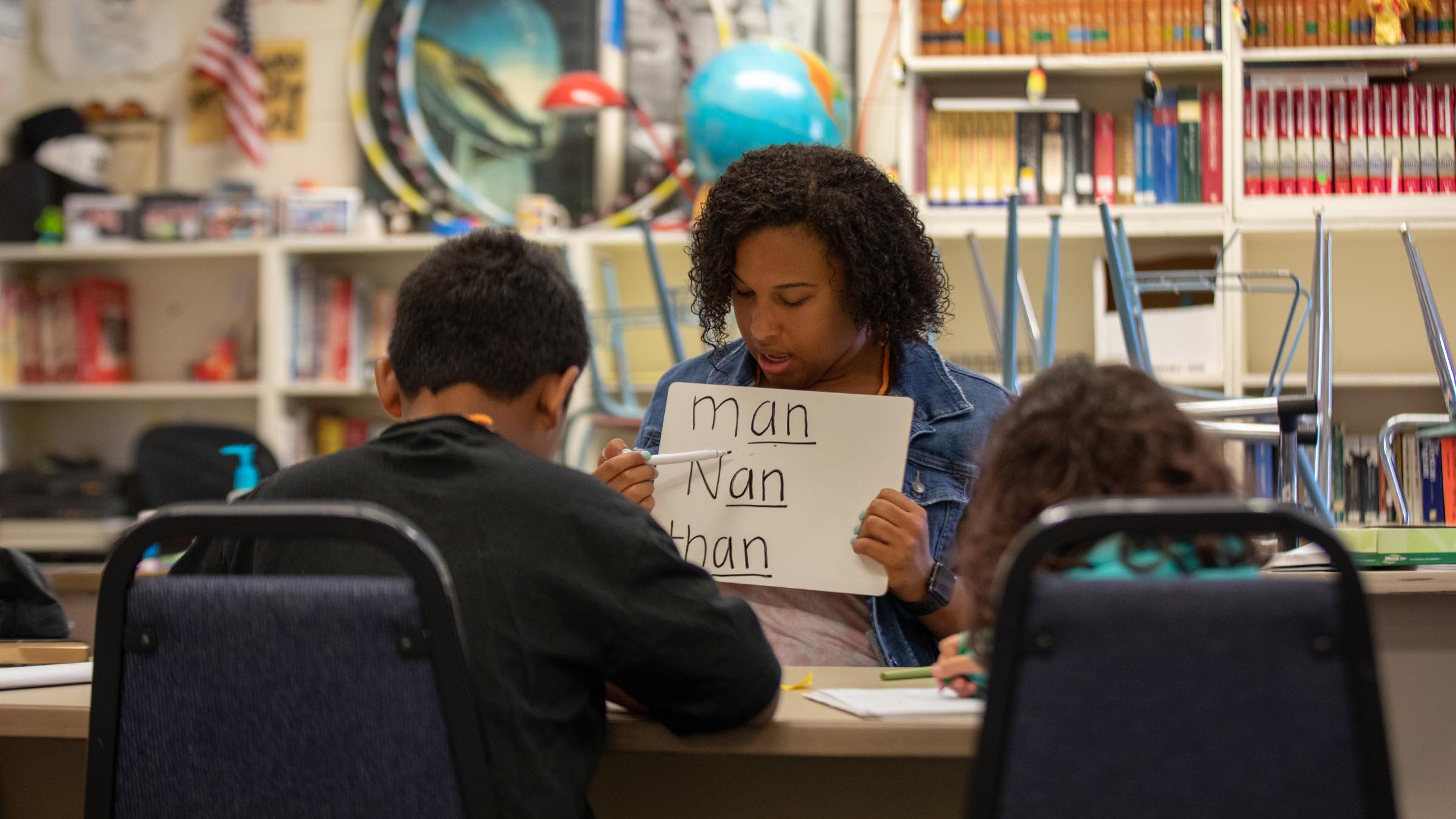 Student leading a literacy activity with children using written word examples