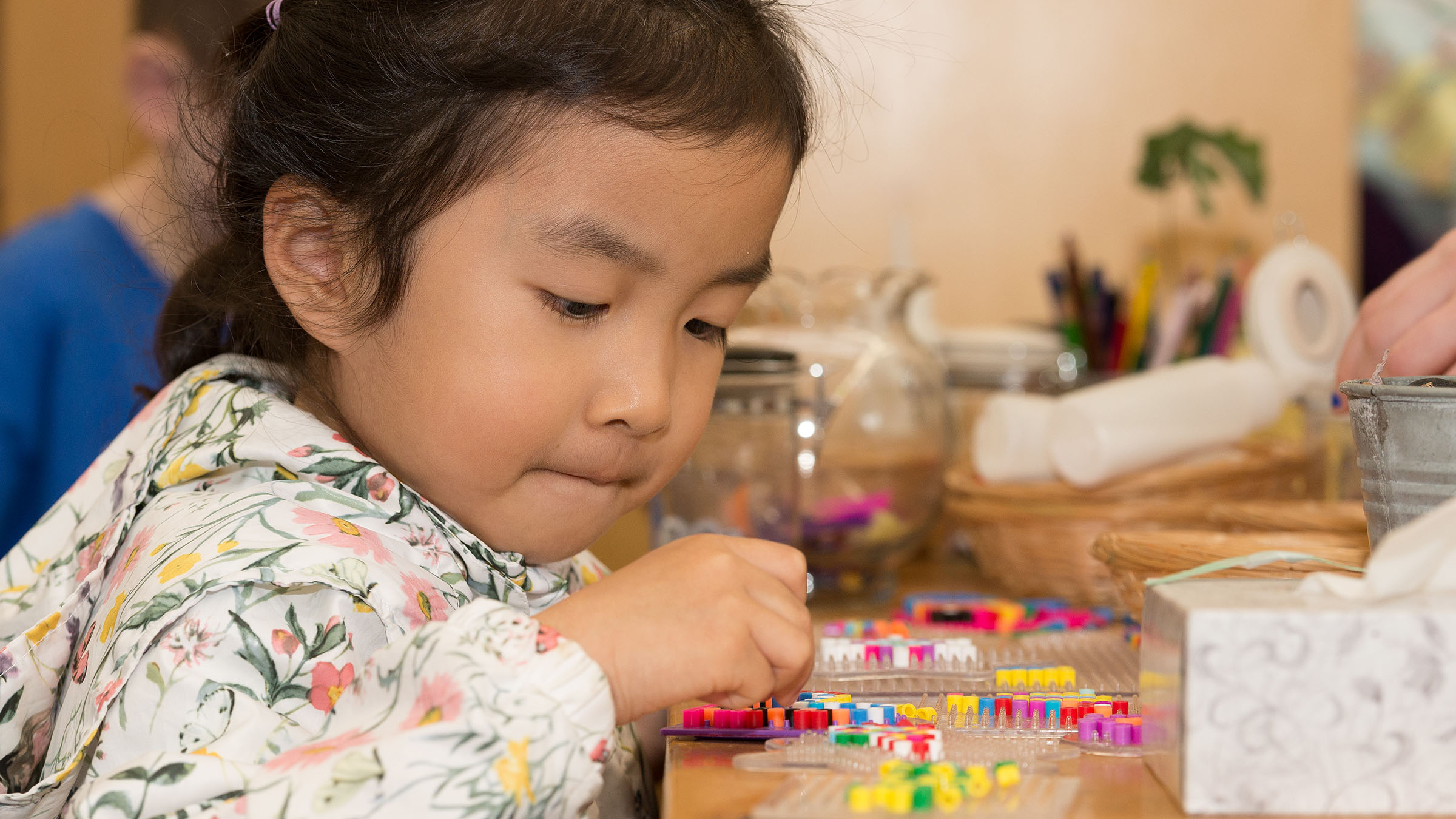 Child concentrates on a colorful bead project