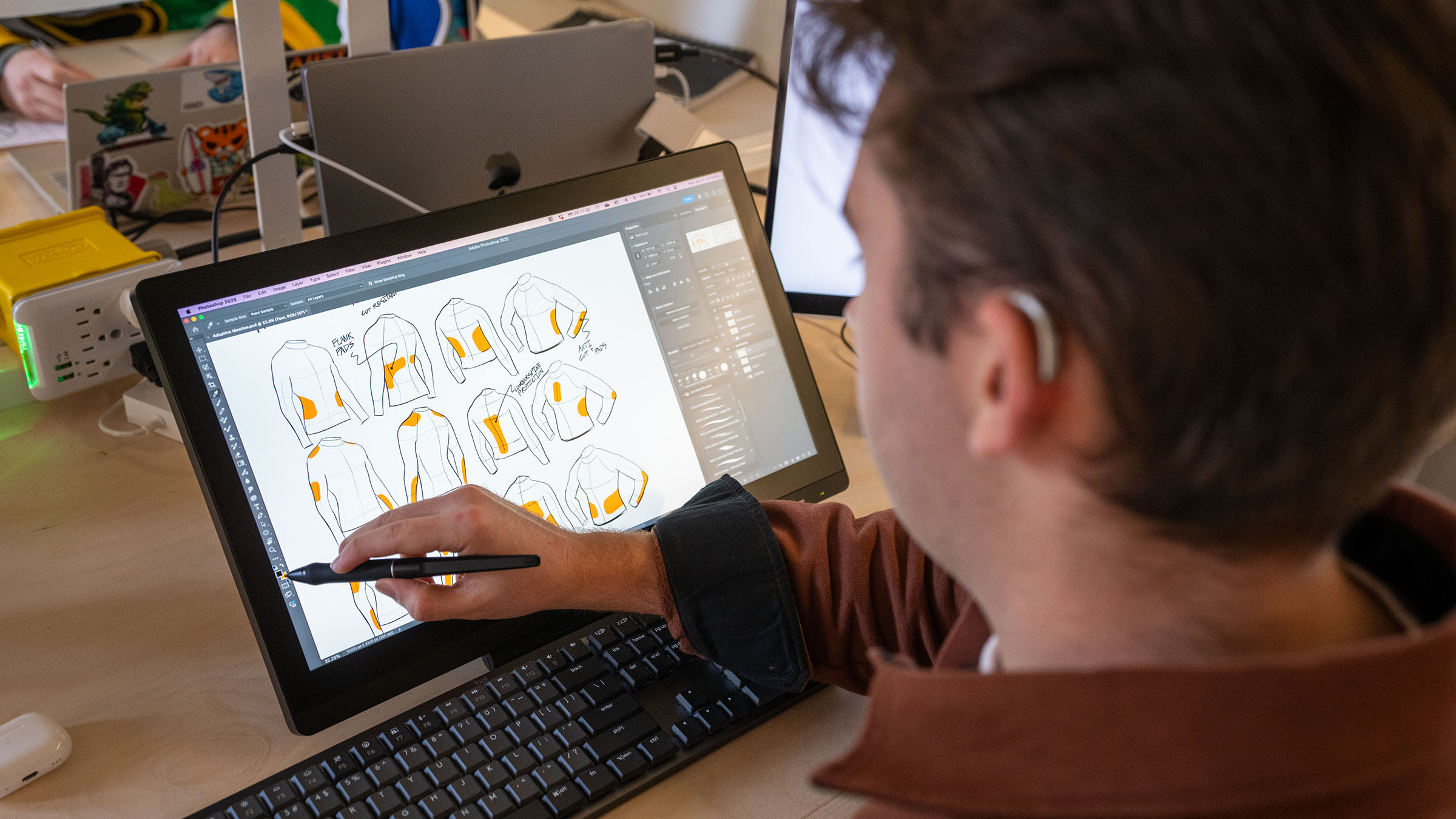 Student using a hearing device creates digital concepts on a drawing tablet, highlighting accessibility and inclusive design