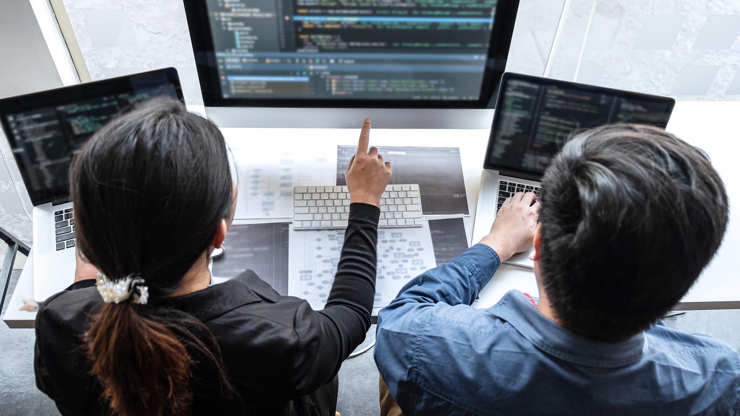Two people at a workstation reviewing code and computational models