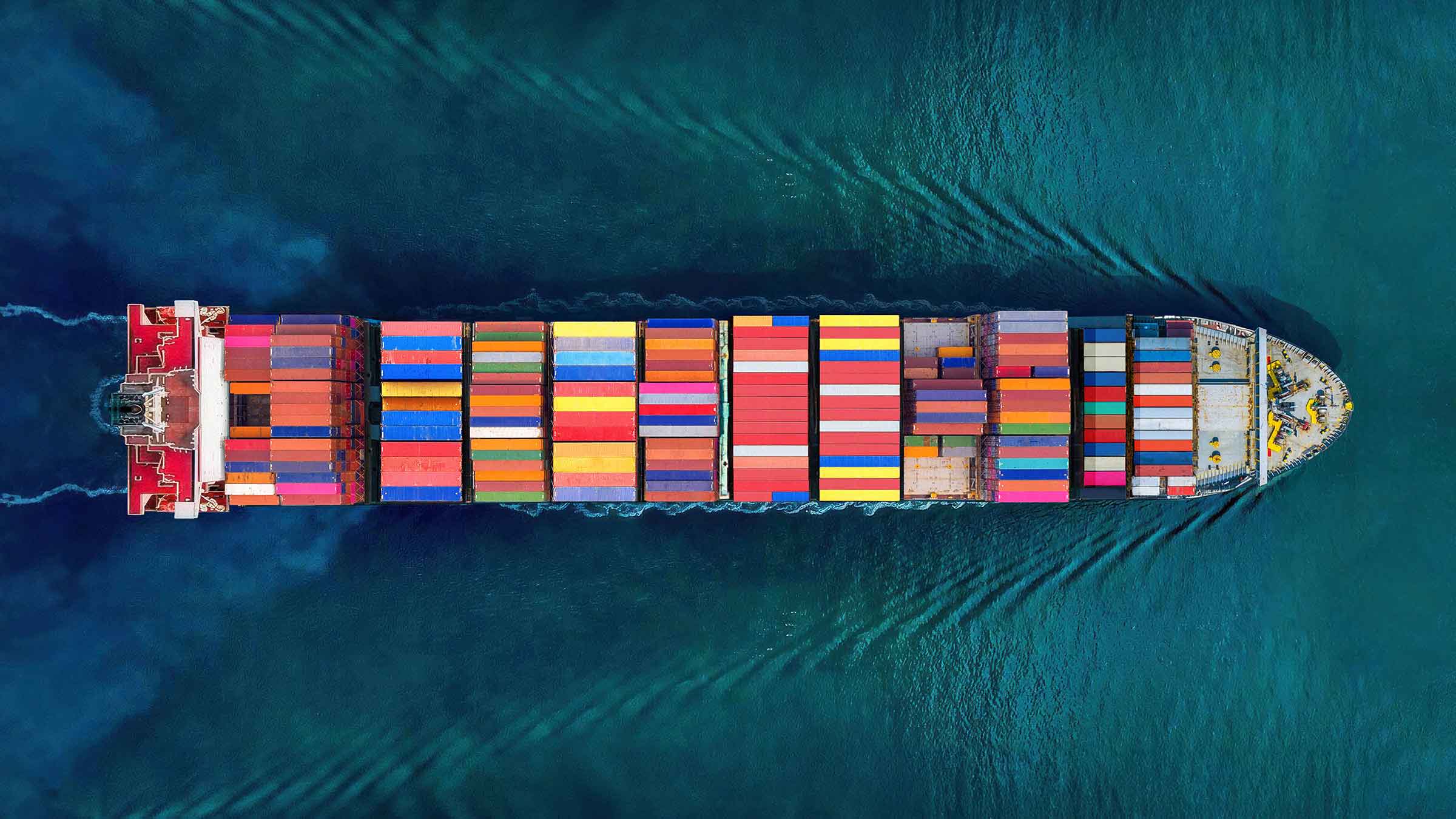 large container ship carrying colorful shipping containers across deep blue water